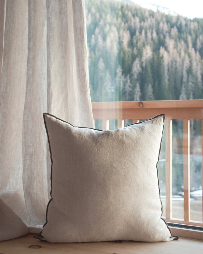 wooden windowsill with curtain and cushions in beige linen fabric, natural panorama in the background - enjoy the synergy of cushions and a curtain in beige linen fabric against a backdrop of natural scenery.