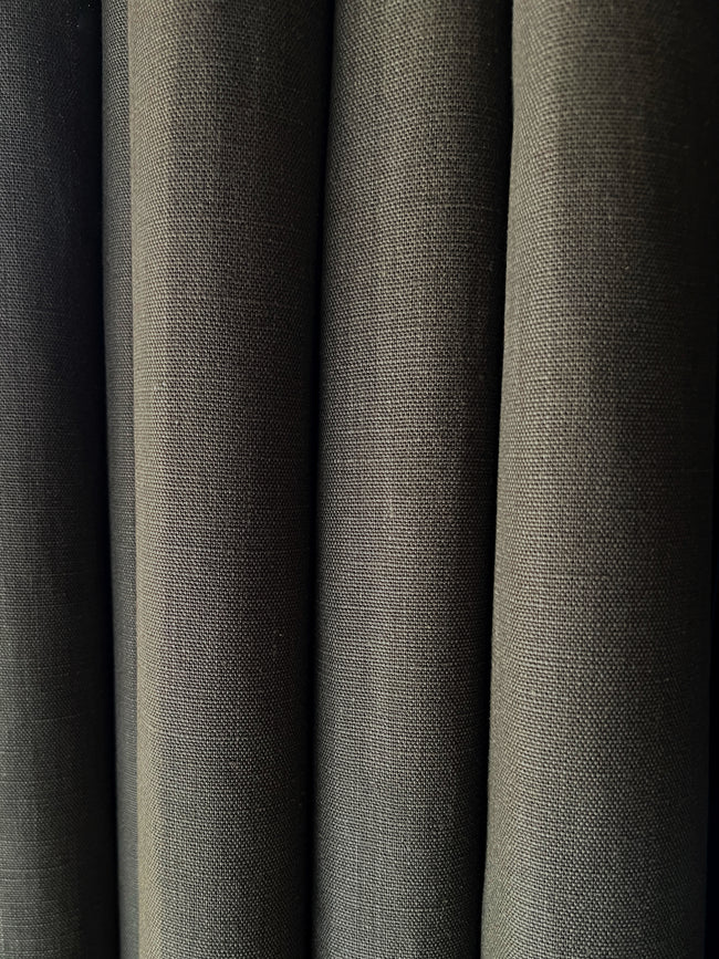 Closeup of linen curtains in the fabric clay cameleon of ann rees - explore the ambiance of a rich dark green linen fabric.